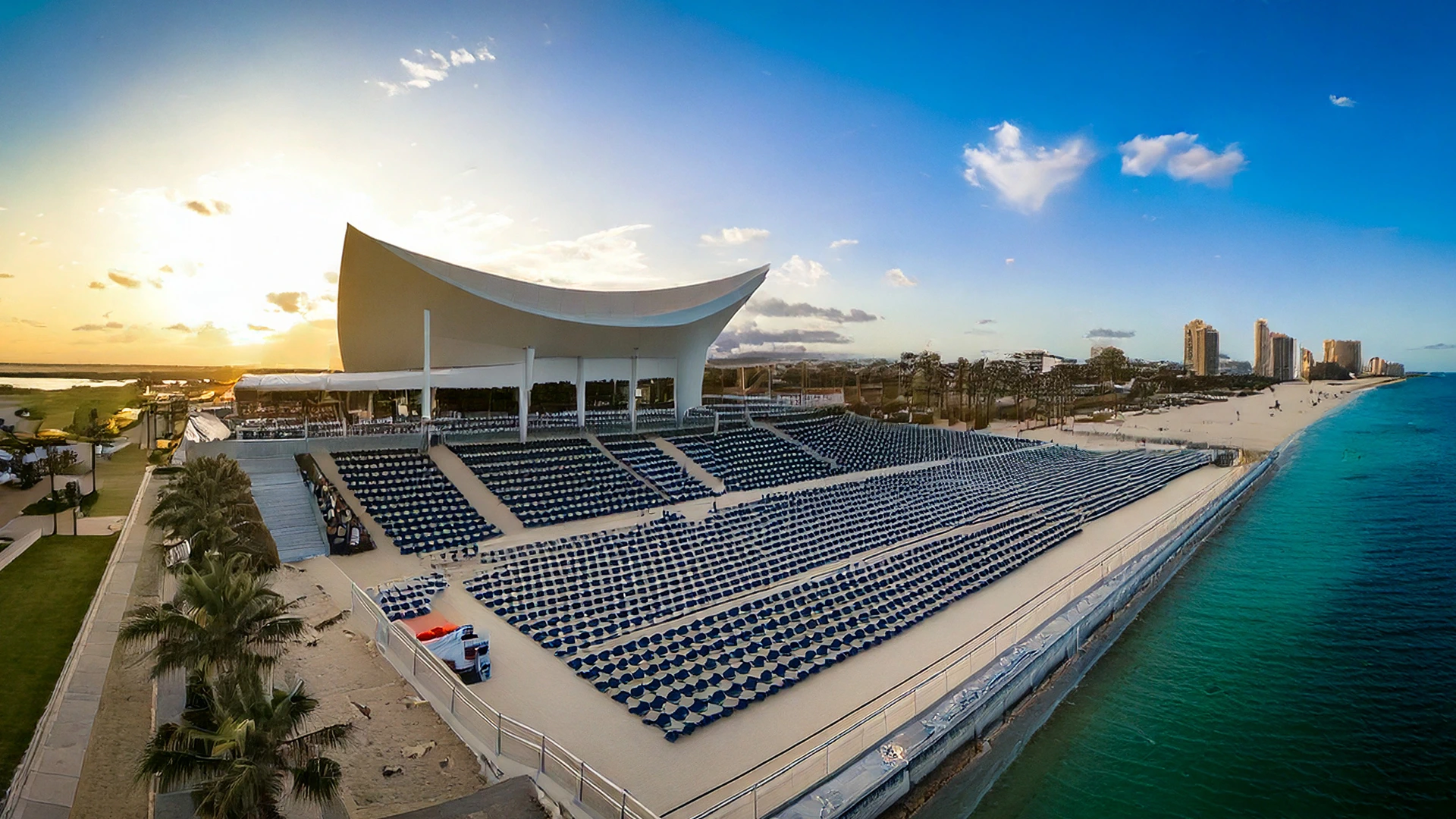 a large outdoor pompano beach stadium with blue chairs and a large white structure